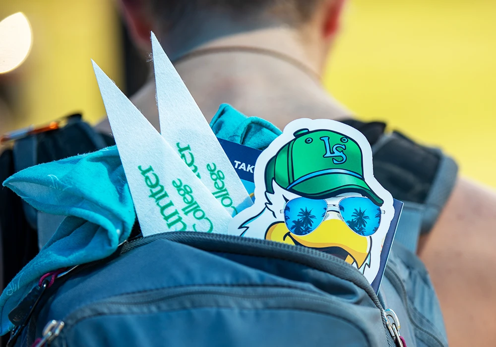 Student wearing backpack with LSSC swag sticking out the back.