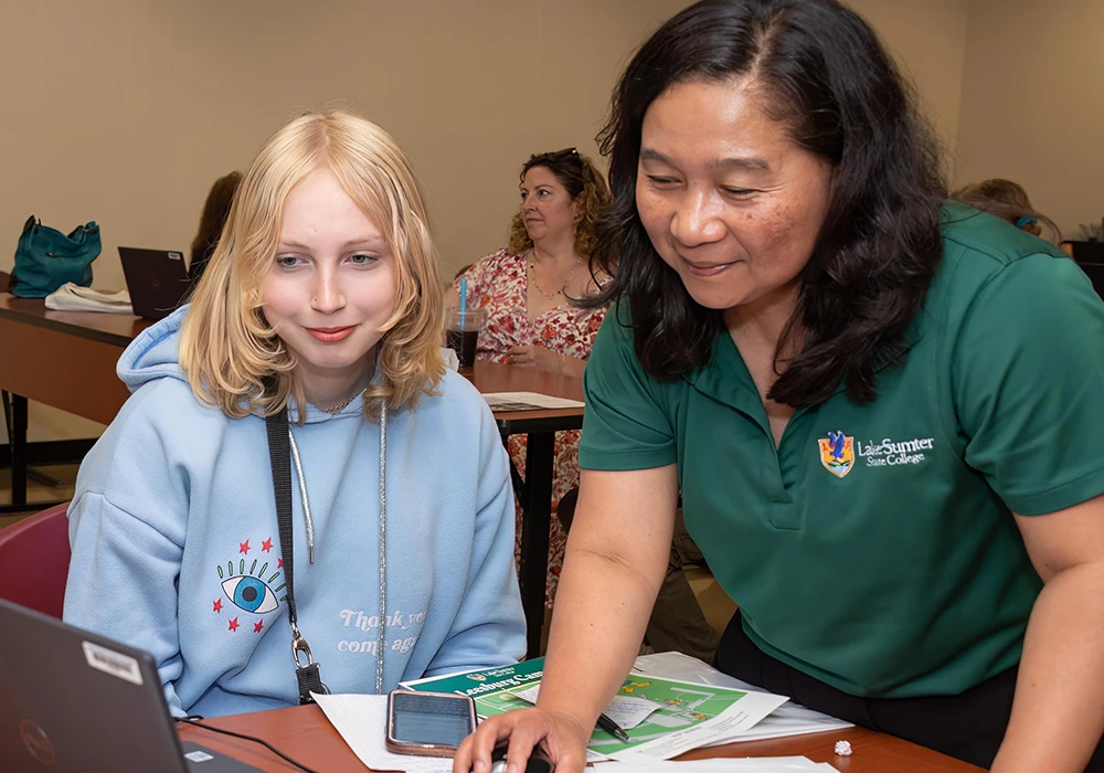 Professor assisting student with work at a computer.